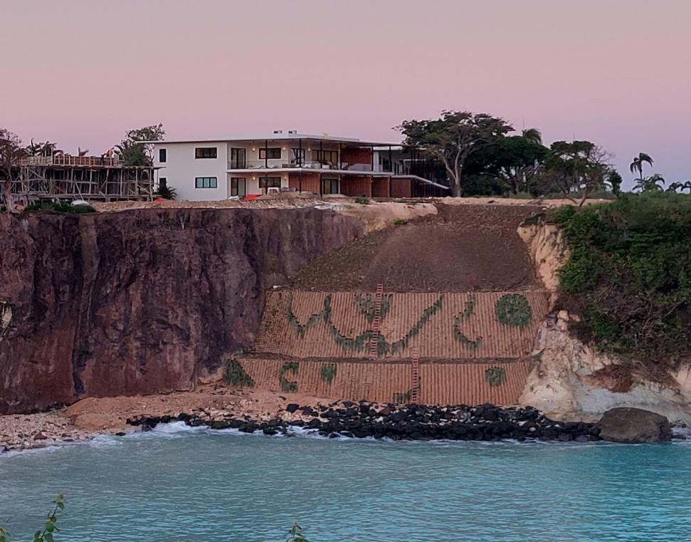 A cliffside building above the sea with planted slopes
